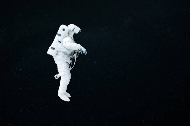 宇宙飛行士は暗い星空の下でオープンスペースを飛行します。宇宙飛行士は任務を開始する。コスモスと人間 - 写真・画像