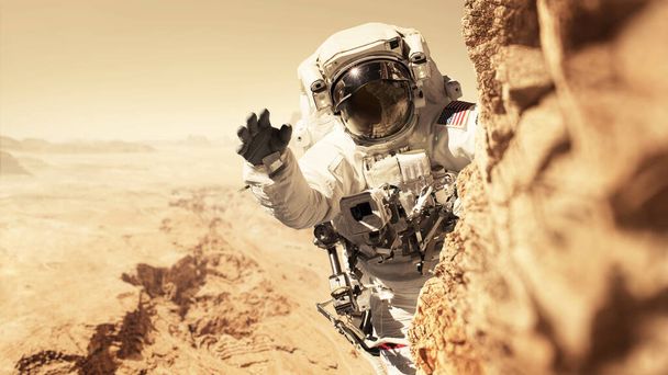 Astronot Marslı Kızıl Gezegen 'de bir görevdedir ve bir kayanın üzerindeki dağa tırmanır. Uzay adamı yeni Mars gezegenini fetheder ve nüfusu çoğaltır. Mars gezegeni ve insanlar, konsept. Yeni eve hoş geldiniz.  - Fotoğraf, Görsel