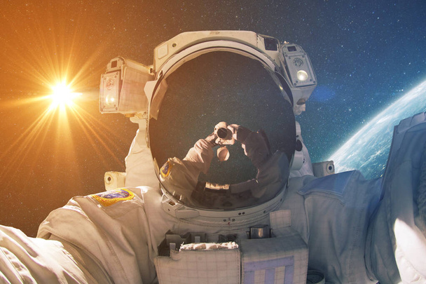 El hombre del espacio hace foto selfie en el espacio exterior con el sol y el planeta tierra. Astronauta fotógrafo viaja y toma fotos en el espacio profundo. Concepto de viaje - Foto, Imagen