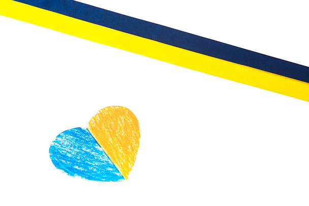 Kolorowa niebiesko-żółta tasiemka tkaninowa i papierowe serce, malowane w kolorze flagi Ukrainy. izolowany na biało Symbol państwa. Leżeć płasko, leżeć. Odbiór. Proszek krajowy - Zdjęcie, obraz