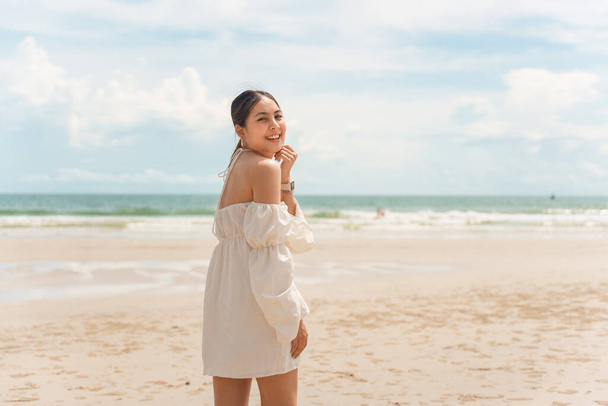 Heureuse jeune femme asiatique en robe jouissant sur la plage en vacances d'été - Photo, image