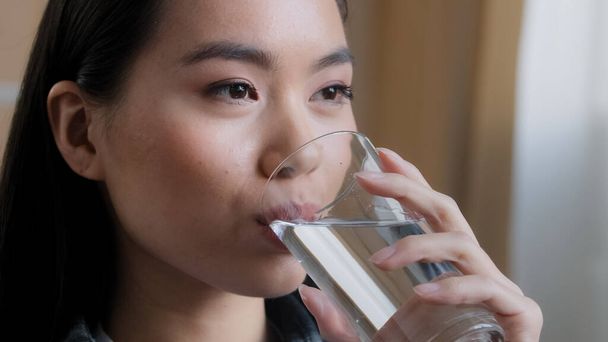 Zblízka asijské žena pití čisté vody domů dodání držení skla oběd ráno denní rituál dobrý zvyk dívka cítí žízeň zdravotní péče hydratace dehydratace osvěžení nápoj usměvavý pocit dobrý - Fotografie, Obrázek