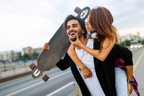 Portrait of young couple with skateboard and longboard having fun together outdoors - Foto, Bild