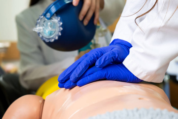 Tıp öğrencileri acil durumlar için tıbbi bir oyuncak bebek üzerinde acil kardiyopulmoner canlandırma uyguluyorlar. - Fotoğraf, Görsel