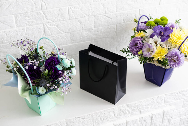 black empty paper bags and bouquets. Blank wall - Foto, Bild