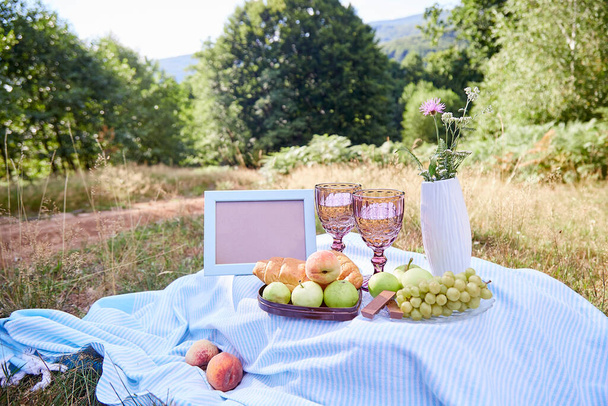 Summer picnic with croissants, fruits, chocolate and glass of wine in the evening forest. Mock up frame, place for your text. Cottage core aesthetic. Summer vibe - Foto, Imagem