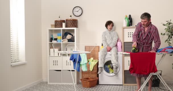 Familie, Vater und Sohn bügeln auf Bügelbrett in Waschküche Familienaktivitäten, Hausarbeit, Wasch- und Reinigungskonzept. - Filmmaterial, Video