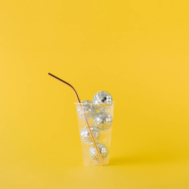Прозрачный пластиковый стакан, наполненный блестящими дискотечными шариками - Фото, изображение