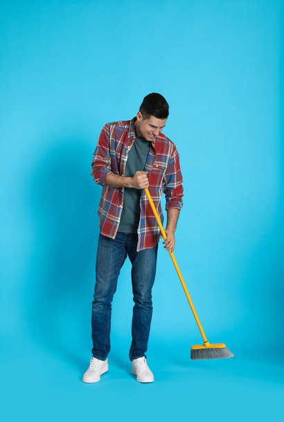 Man with yellow broom on light blue background - Photo, image