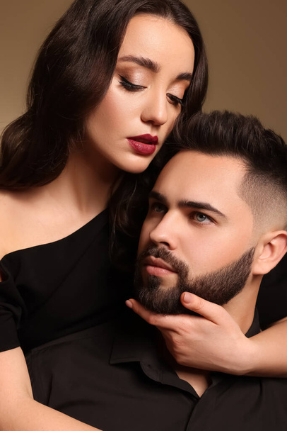 Handsome bearded man with sexy lady on brown background, closeup - 写真・画像