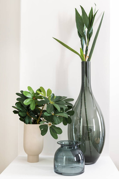 Esquina decorada una casa con jarrones de vidrio y porcelana con plantas artificiales y flores - Foto, Imagen