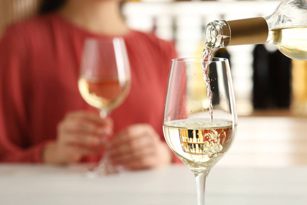 Woman at table in restaurant, focus on pouring wine into glass, closeup - Foto, immagini
