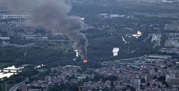 flames of the fire near the city in evening and black dense smoke in evening - Photo, Image