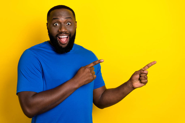 Portrait of attractive cheerful amazed guy demonstrating copy space idea isolated over bright yellow color background - Photo, Image