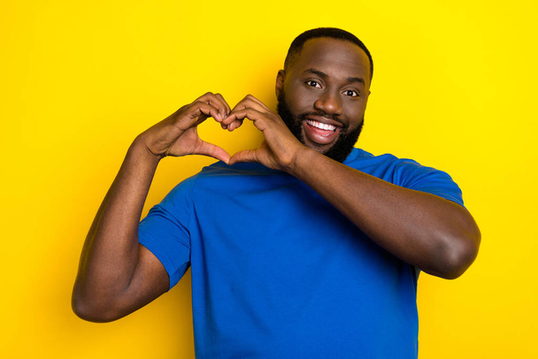 Portrait of attractive cheerful guy showing heart sign amour romance 14 February isolated over vivid yellow color background - Фото, изображение