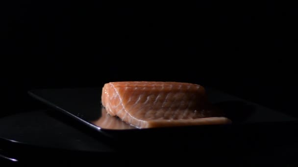 Raw pink salmon fillet steak on a black tray gyrating - Footage, Video