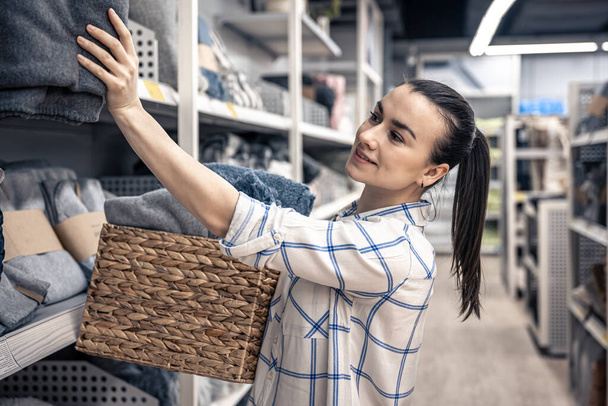 Молода жінка з плетеним кошиком, повним ковдр в магазині благоустрою будинку
. - Фото, зображення