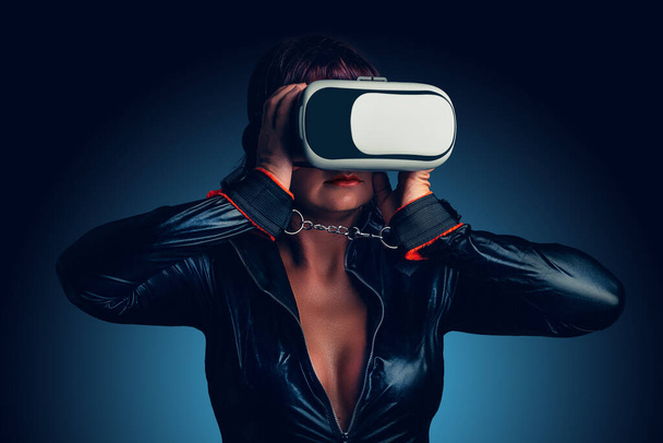 Femme sexy avec menottes et robe en latex profitant de la réalité virtuelle à la maison. Concept Amour virtuel - Photo, image