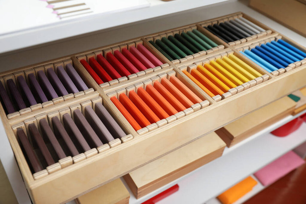 Wooden box with color tablets and other montessori toys on shelves - Photo, Image