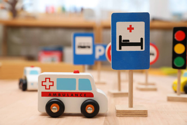 Different miniature road signs and cars on wooden table, closeup. Montessori toy - Φωτογραφία, εικόνα