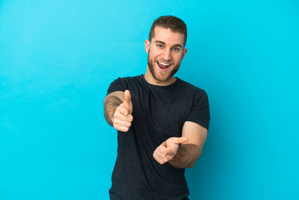 Young handsome caucasian man isolated on blue background pointing to the front and smiling - Photo, Image