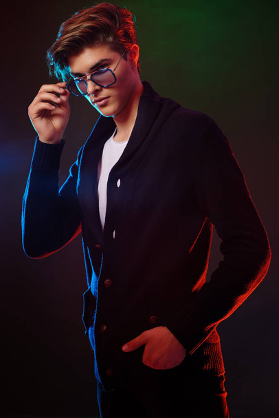 Neon ritratto luminoso di bel modello maschile con capelli scuri di media lunghezza, acconciatura, indossare occhiali da sole - Foto, immagini