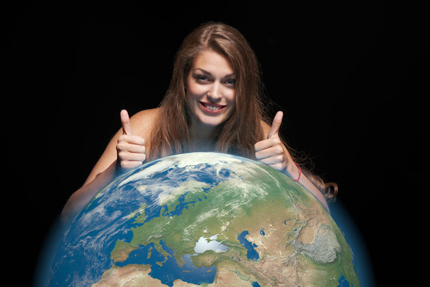 Woman with earth globe gesturing thumb up - Φωτογραφία, εικόνα