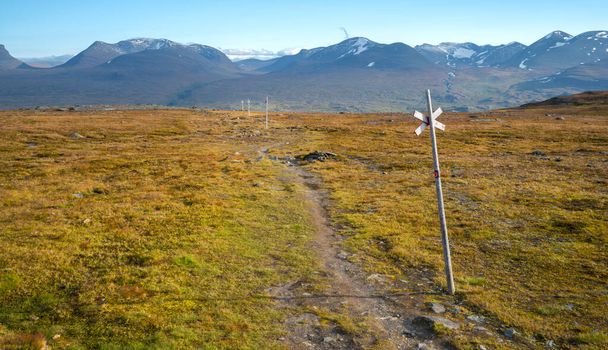 Wooden markers on Nuolja, or Njulla mountain, in Abisko National Park in arctic Sweden. Adventure in remote arctic wilderness. Hiking in Swedish Lapland. Beautiful day of arctic summer. - Foto, afbeelding
