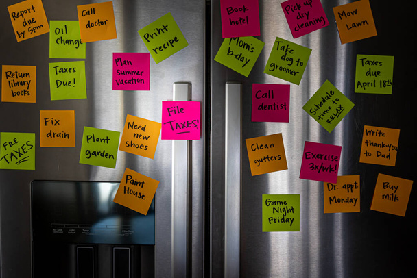 Puerta del refrigerador con notas de memorándum de colores que recuerdan a presentar impuestos - Foto, Imagen