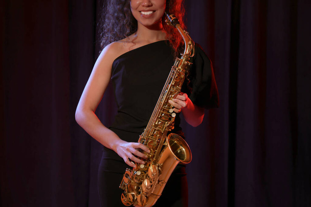 African American woman with saxophone on dark background, closeup - Valokuva, kuva