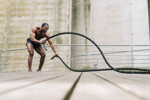 İp savaşı ipi olan Afro-Amerikalı erkekler fitness salonunda ip egzersizi yapıyorlar. CrossFit konsepti. Spor, spor, halat, antrenman, atlet, egzersiz, egzersiz, egzersiz konsepti. - Fotoğraf, Görsel