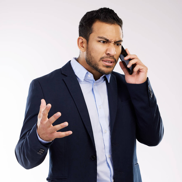 Dont make your problem my problem. Studio shot of a young businessman looking angry while talking on a cellphone against a white background. - Photo, image