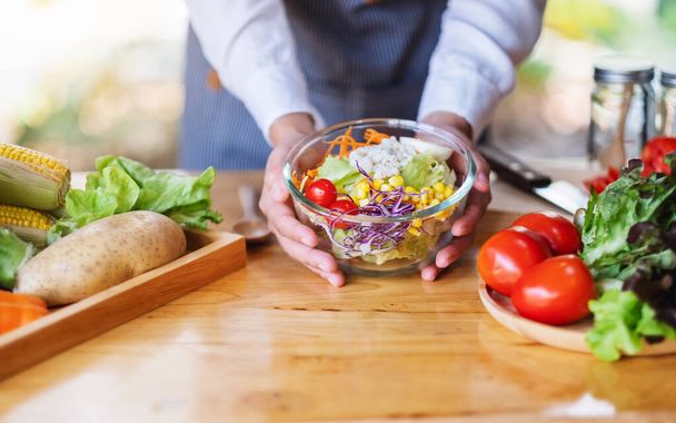 Nahaufnahme einer Köchin, die in der Küche eine Schüssel mit frischem gemischtem Gemüsesalat hält - Foto, Bild