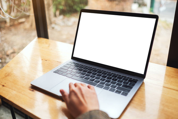 Imagen burlona de una mujer usando y tocando el panel táctil de la computadora portátil con pantalla de escritorio blanca en blanco en la mesa de madera - Foto, imagen