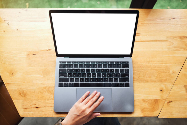 Top view mockup image of a woman using and touching on laptop touchpad with blank white desktop screen on wooden table - Photo, Image