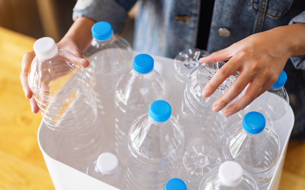Uma mulher recolhendo e separando garrafas de plástico de lixo reciclável em uma lixeira em casa - Foto, Imagem
