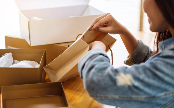 Closeup image of a woman opening and looking inside shopping bag at home for delivery and online shopping concept - Foto, Imagem