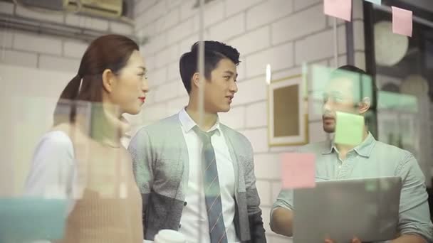 kleine groep van Aziatische ondernemers bespreken zakelijke strategieën met behulp van plakkerige notitie in kantoor vergaderzaal.  - Video