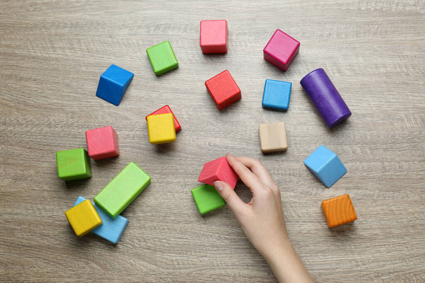 ABA therapist with colorful building blocks at wooden table, top view - Fotoğraf, Görsel