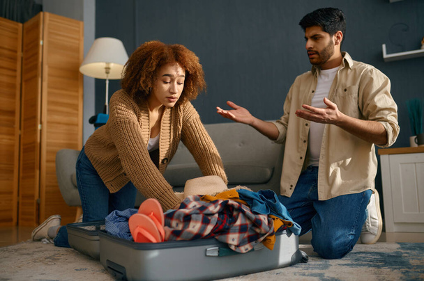 Couple trying to pack belongings into suitcase - Fotoğraf, Görsel