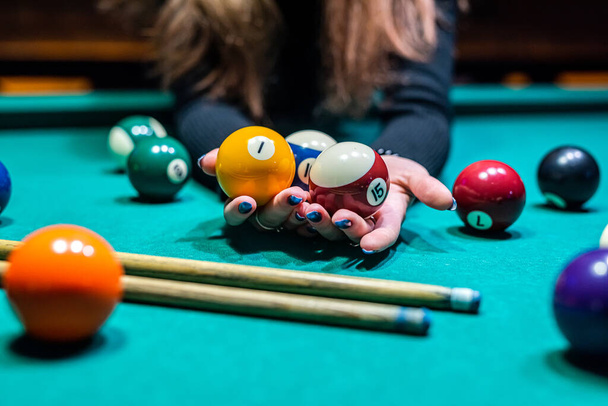 hands of a beautiful young slender girl beautifully chasing billiard balls on a spacious table in the billiard room. Billiards concept - Photo, Image