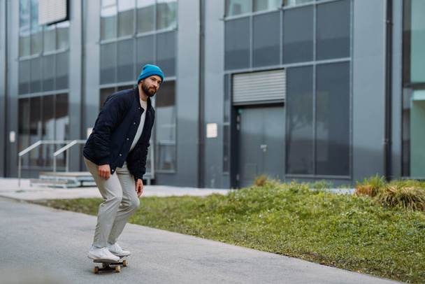 O homem anda de skate. Edifício moderno no fundo - Foto, Imagem