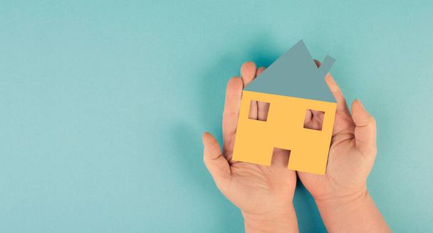 Hausmodell in der Hand auf blauem Hintergrund. Konzept von Immobilien, Immobilien, Wohnungen, Familie, Eigenheim - Foto, Bild