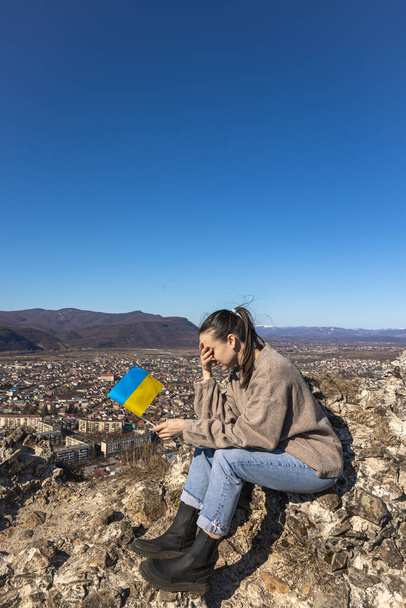 都会の風景を背景にウクライナの旗を持つ若い女性. - 写真・画像