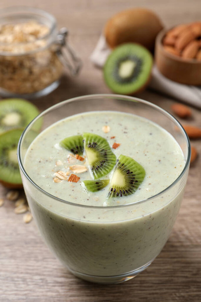 Glass of tasty kiwi smoothie with oatmeal on wooden table, closeup - Foto, Imagem