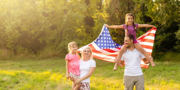 Patriotic holiday. Happy family, mother and daughters with American flag outdoors on sunset. USA celebrate independence day 4th of July. - Fotografie, Obrázek