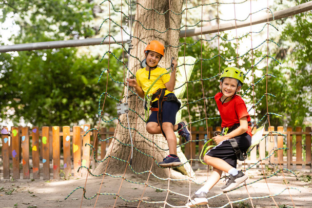 Happy child climbing in the trees. Rope park. Climber child. Early childhood development. Roping park. Balance beam and rope bridges. Rope park - climbing center - Zdjęcie, obraz