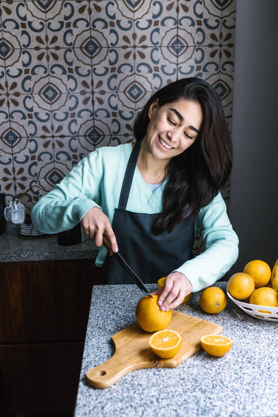 Hispanic young latin woman preparing orange juice at the kitchen in Mexico Latin America - 写真・画像