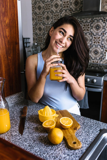 Hispanic young latin woman preparing orange juice at the kitchen in Mexico Latin America - Fotoğraf, Görsel