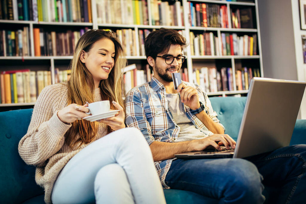 Schönes junges Paar mit Laptop im Café, sie shoppen online mit Kreditkarte. - Foto, Bild